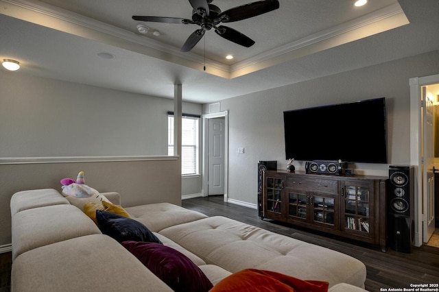 living room with crown molding, a raised ceiling, baseboards, wood finished floors, and a ceiling fan