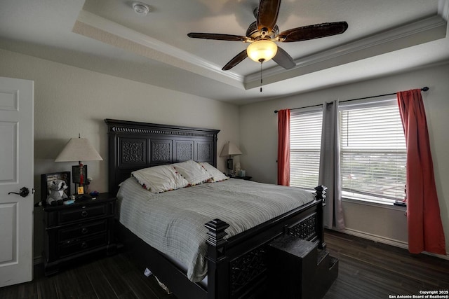 bedroom featuring dark wood finished floors, ornamental molding, ceiling fan, and a tray ceiling