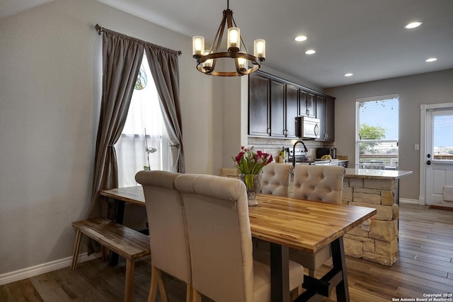 dining space with light wood finished floors, recessed lighting, a notable chandelier, and baseboards