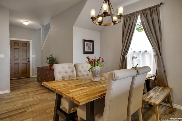 dining area with a notable chandelier, baseboards, and light wood-style floors