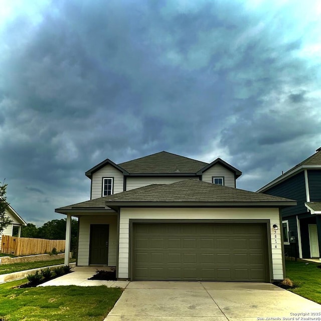 traditional-style home with fence, a shingled roof, a garage, a front lawn, and concrete driveway