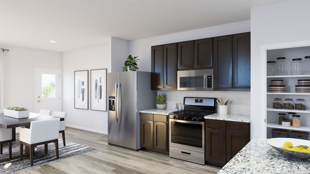 kitchen featuring appliances with stainless steel finishes, dark brown cabinets, light stone countertops, light wood finished floors, and recessed lighting