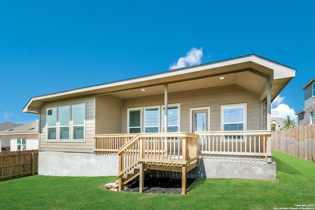 rear view of property with a lawn, a wooden deck, and a fenced backyard