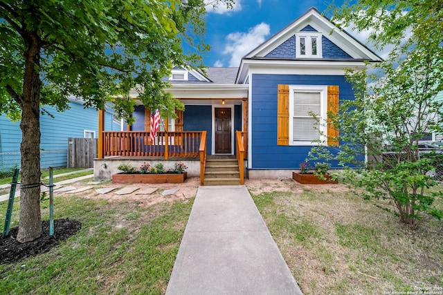 view of front of house featuring a porch, a front lawn, and fence