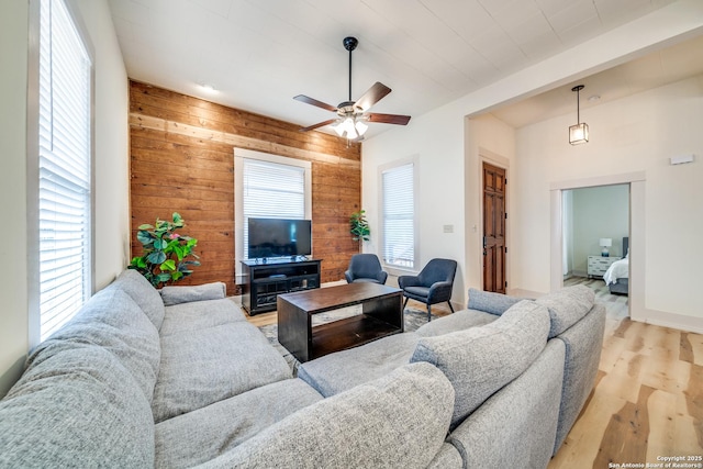 living room featuring wooden walls, ceiling fan, and light wood-type flooring