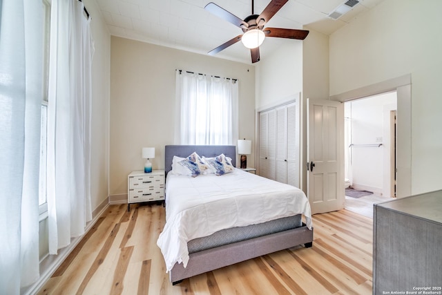 bedroom featuring connected bathroom, light wood-style floors, a closet, a ceiling fan, and visible vents