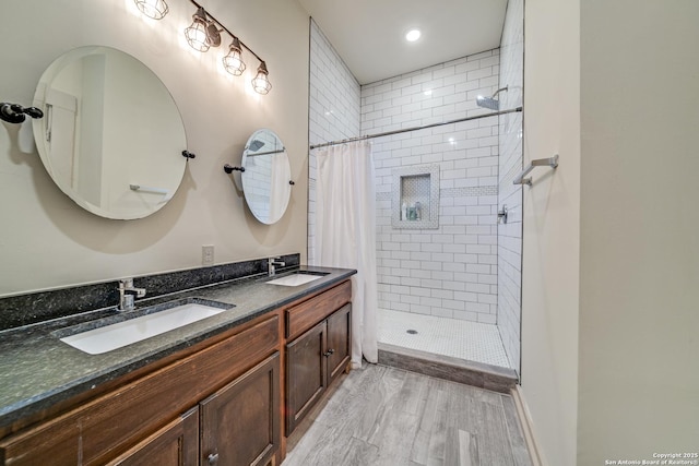 full bathroom featuring recessed lighting, wood finished floors, double vanity, a sink, and a stall shower