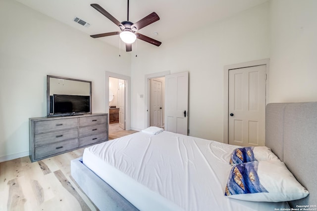 bedroom with connected bathroom, light wood-style flooring, ceiling fan, baseboards, and visible vents