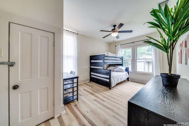 bedroom with light wood finished floors, ceiling fan, and baseboards