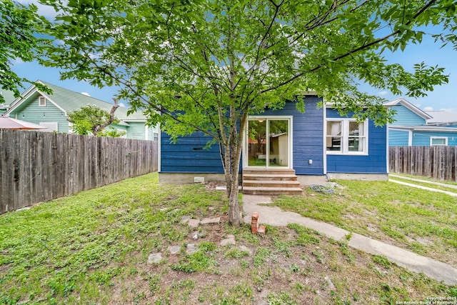 view of front facade with a front yard, entry steps, and a fenced backyard