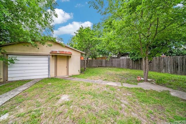view of yard with an outdoor structure, driveway, a garage, and a fenced backyard
