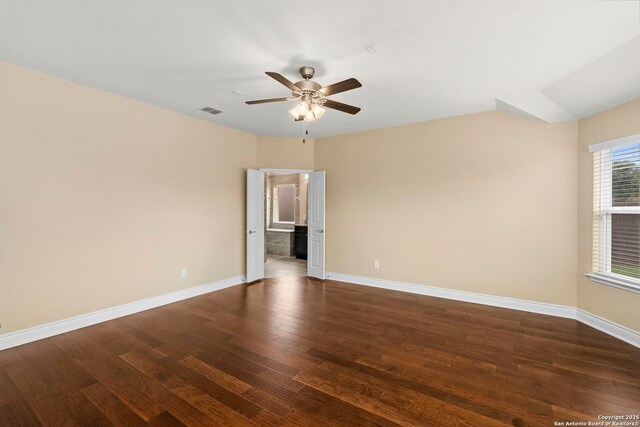 spare room with visible vents, a ceiling fan, dark wood finished floors, and baseboards