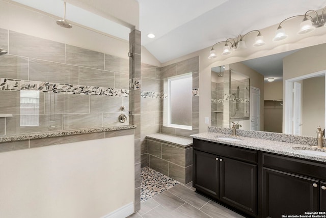 bathroom featuring double vanity, a walk in shower, vaulted ceiling, and a sink