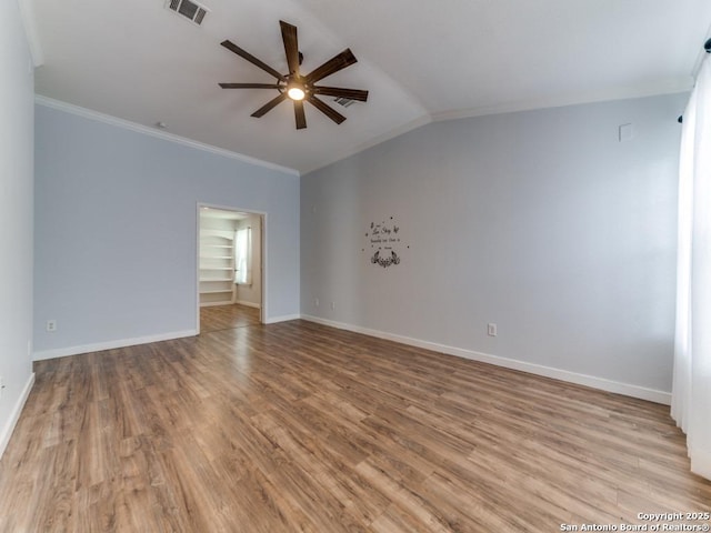 empty room with crown molding, a ceiling fan, wood finished floors, and baseboards