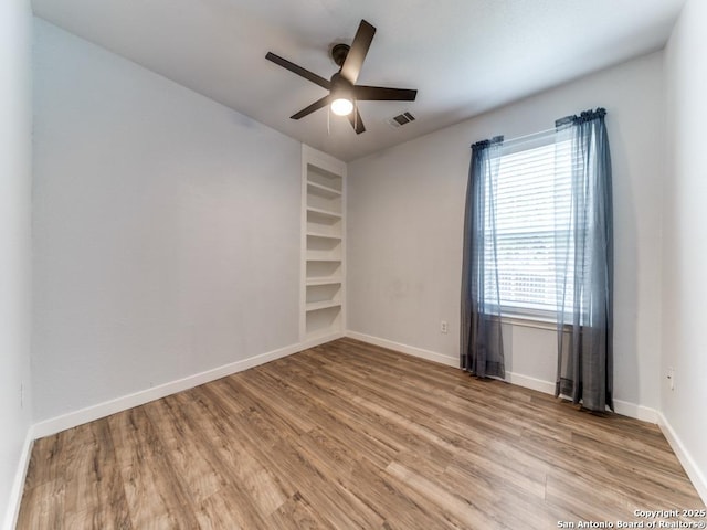 empty room with baseboards, visible vents, ceiling fan, and light wood-style flooring