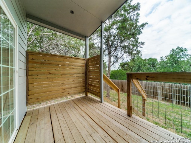 wooden terrace with a fenced backyard