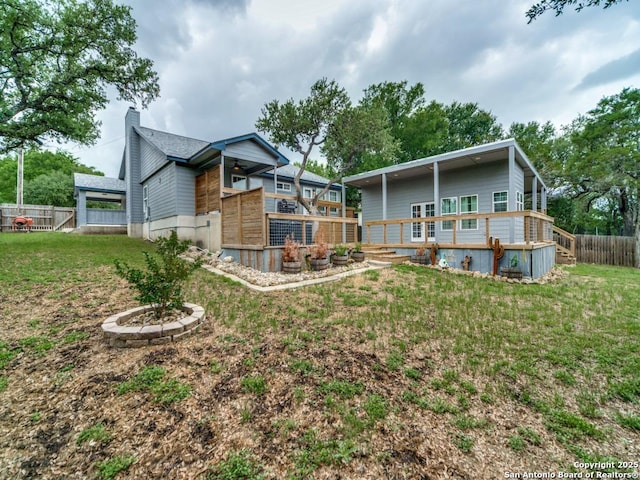 back of house featuring a chimney, a fenced backyard, a yard, a wooden deck, and a ceiling fan