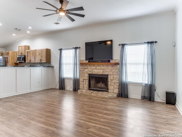 unfurnished living room featuring visible vents, wood finished floors, a healthy amount of sunlight, and a fireplace