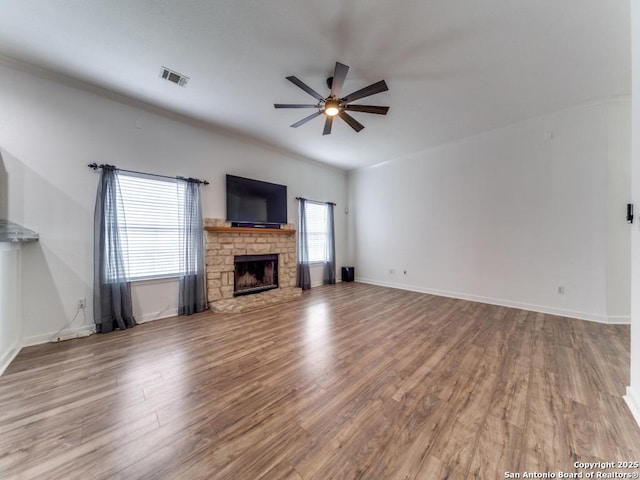 unfurnished living room featuring a fireplace, a ceiling fan, visible vents, baseboards, and wood finished floors