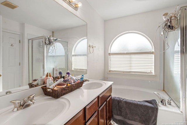 full bathroom with double vanity, visible vents, a stall shower, and a sink