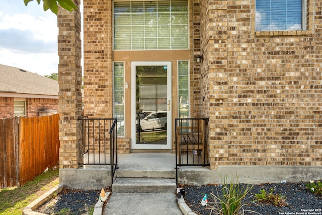 property entrance featuring fence and brick siding