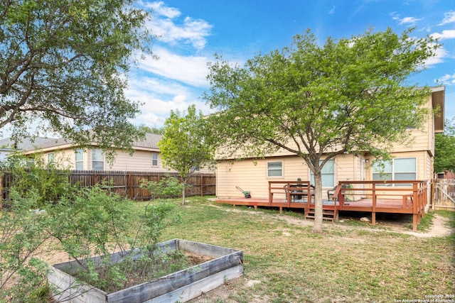 rear view of house with a vegetable garden, a yard, a wooden deck, and a fenced backyard