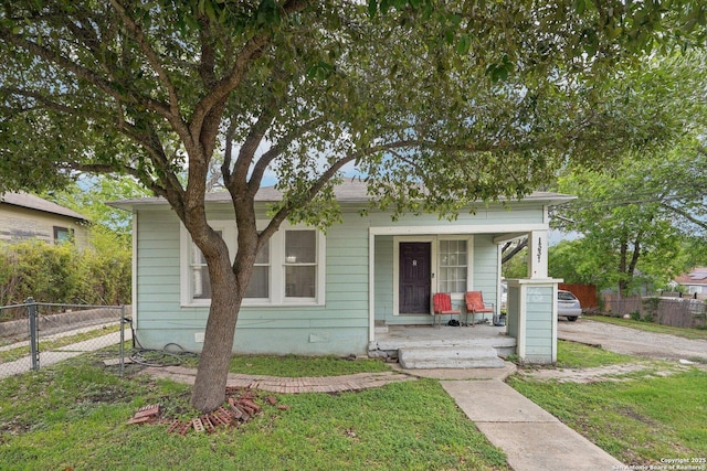 bungalow-style house with fence, covered porch, and a front yard