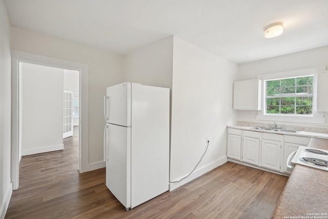 kitchen with a sink, light wood-style floors, white cabinetry, light countertops, and freestanding refrigerator