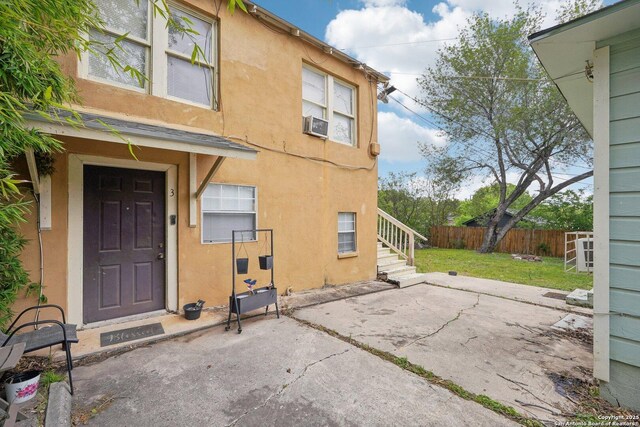 doorway to property with stucco siding, fence, and a lawn