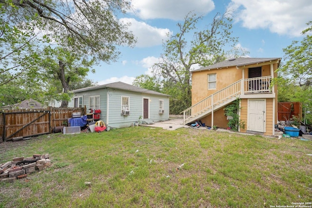 back of property featuring stairway, an outdoor fire pit, a lawn, stucco siding, and fence