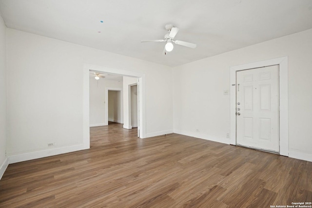 empty room featuring a ceiling fan, baseboards, and light wood-type flooring
