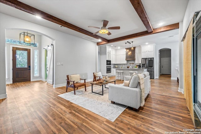 1547 Moon Vw, New Braunfels, TX 78132 - living area featuring arched walkways, beamed ceiling, baseboards, wood finished floors, and a ceiling fan