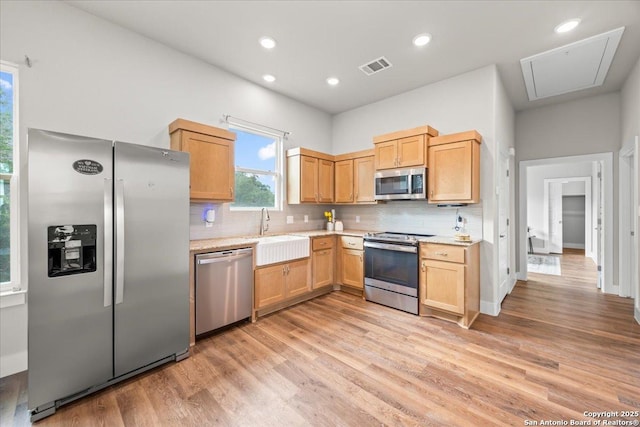 1547 Moon Vw, New Braunfels, TX 78132 - kitchen with appliances with stainless steel finishes, a sink, light wood-style floors, tasteful backsplash, and light brown cabinets