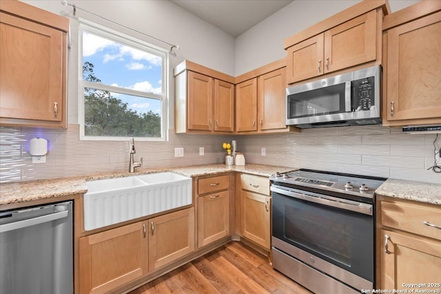 1547 Moon Vw, New Braunfels, TX 78132 - kitchen featuring appliances with stainless steel finishes, a sink, backsplash, and light wood-style floors