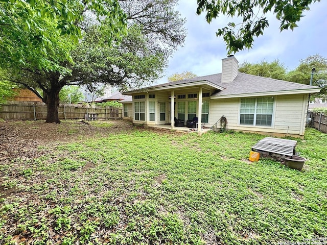 607 Dover Ln, Round Rock, TX 78664 - rear view of property with a chimney, a patio area, roof with shingles, a lawn, and a fenced backyard