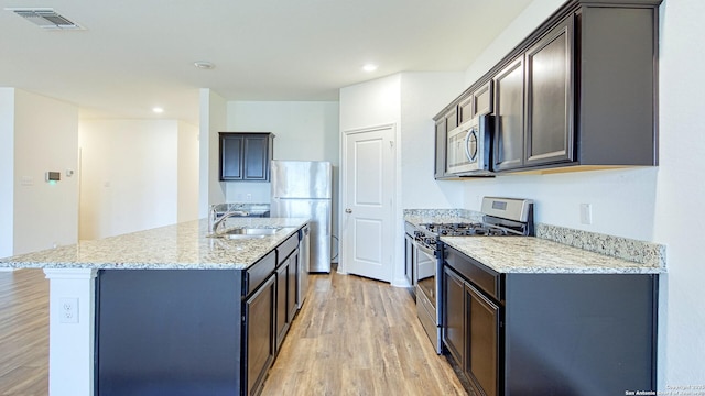 13406 Flower Pond, Saint Hedwig, TX 78152 - kitchen featuring light stone countertops, light wood-style flooring, appliances with stainless steel finishes, a sink, and visible vents