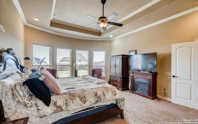 bedroom featuring carpet floors, a glass covered fireplace, a raised ceiling, a textured ceiling, and crown molding