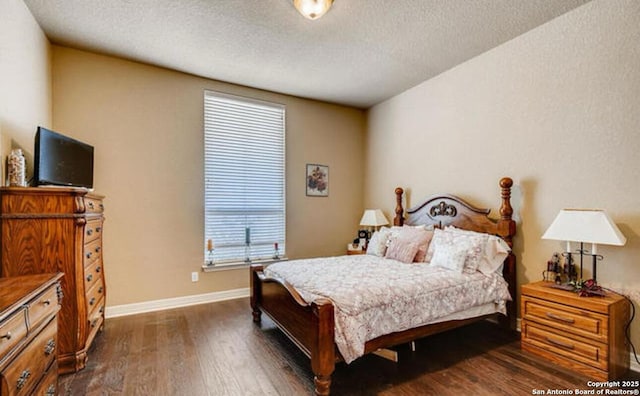 bedroom with baseboards, wood finished floors, and a textured ceiling