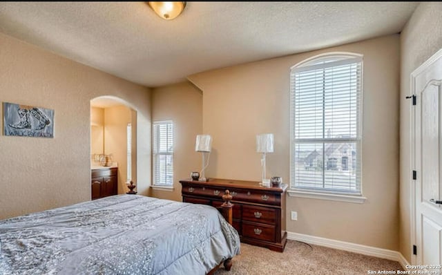 bedroom featuring multiple windows, light carpet, and arched walkways