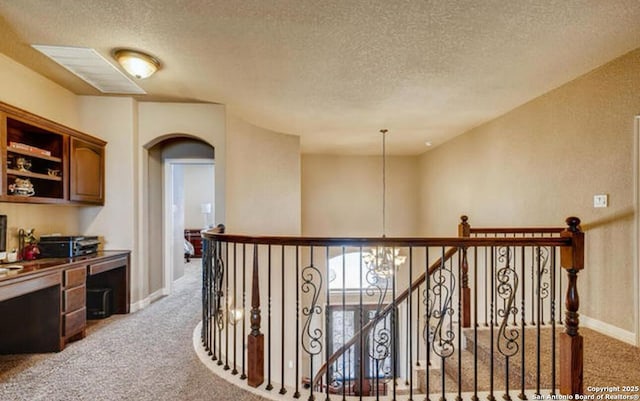 corridor featuring baseboards, arched walkways, light carpet, and a textured ceiling