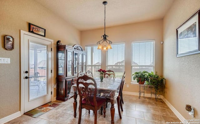 dining area featuring baseboards, light tile patterned floors, an inviting chandelier, and a textured wall