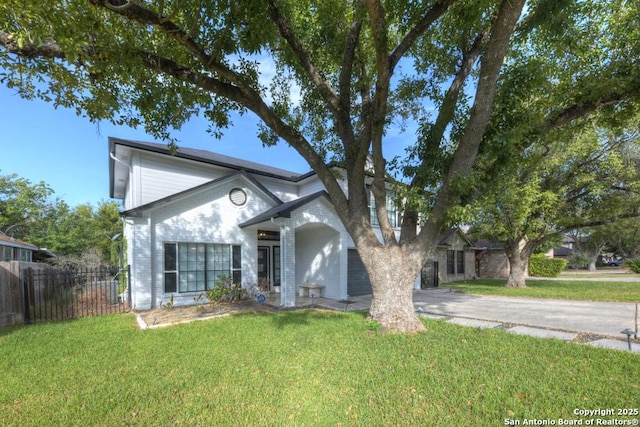 view of front of home featuring driveway, fence, brick siding, and a front lawn