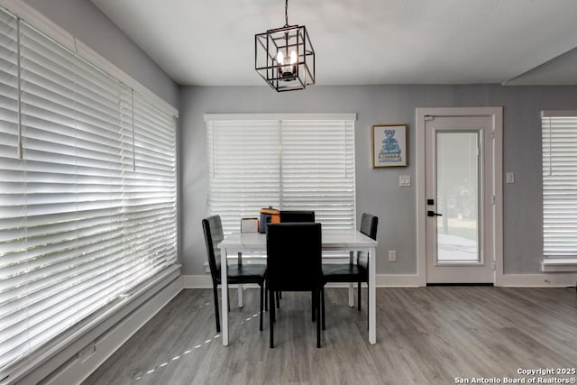 dining area featuring wood finished floors, a notable chandelier, and baseboards