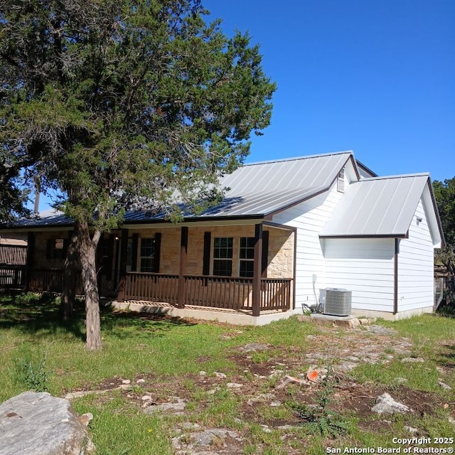ranch-style house with stone siding, cooling unit, a porch, and metal roof