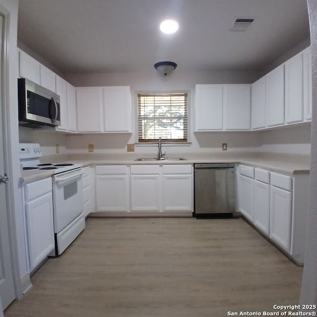 kitchen featuring white cabinetry, stainless steel appliances, light countertops, and a sink