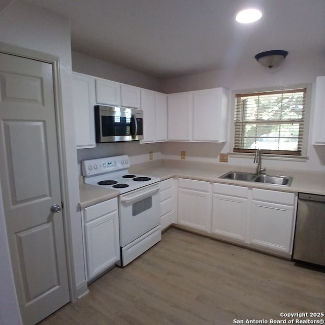 kitchen with a sink, white cabinets, stainless steel appliances, and light countertops