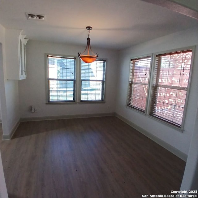 unfurnished dining area featuring baseboards, visible vents, wood finished floors, and a healthy amount of sunlight