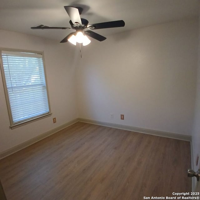 spare room with wood finished floors, ceiling fan, and baseboards
