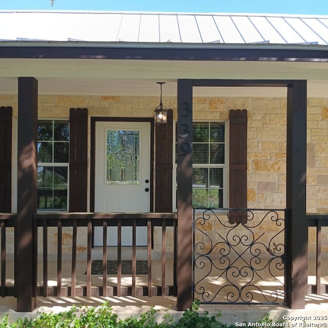 entrance to property featuring metal roof, a standing seam roof, and covered porch