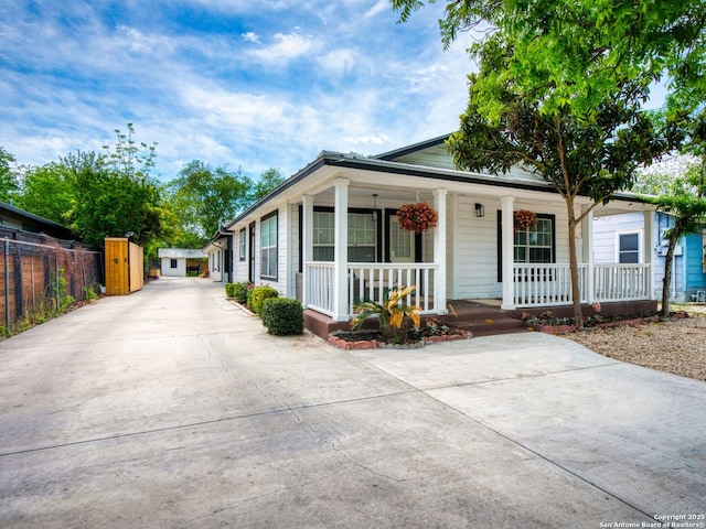 bungalow-style house featuring a porch, concrete driveway, and fence